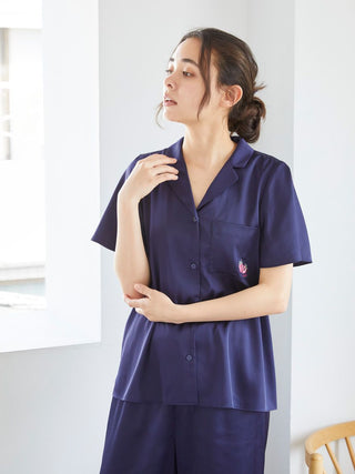 Model wearing navy blue satin sleep shirt with strawberry embroidery by Gelato Pique, showcasing button-up design and soft fabric.