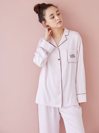 Woman wearing a pink piping satin long sleeve pajama shirt and pants, showcasing elegant comfort and stylish loungewear.