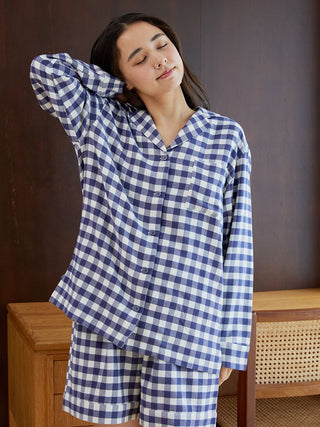 Woman wearing a checkered long sleeve sleep shirt and shorts, showcasing comfortable sleepwear fashion.