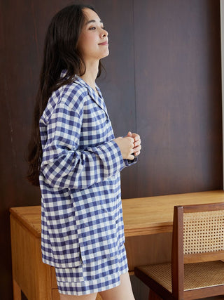 Woman wearing a checkered long sleeve sleep shirt, displaying a cozy and elegant loungewear style in a softly lit room.