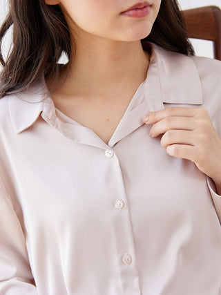 Woman wearing long sleeve satin sleepwear blouse with button-up and pointed collar, showcasing its elegant sheen and relaxed fit.
