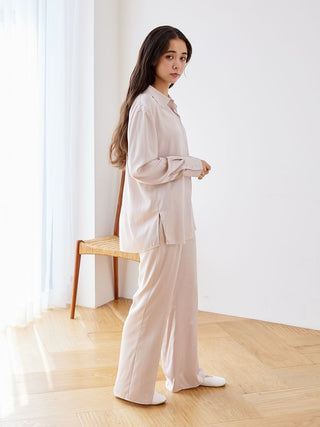 Woman wearing elegant long sleeve satin sleepwear blouse and pants, showcasing relaxed and luxurious loungewear.