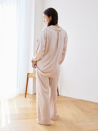 Woman wearing a long sleeve satin sleepwear blouse in a softly lit room.