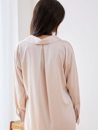 Back view of a woman wearing a long sleeve satin sleepwear blouse in soft pink, showcasing its elegant drape and relaxed fit.