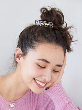 Model wearing Gelato Pique Metal Logo Hair Barrette, featuring 'PIQUE' in black enamel and gold-tone finish, styled in a casual updo.