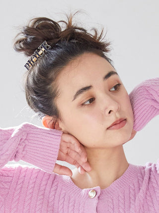 Woman wearing Gelato Pique metal logo hair barrette with black enamel 'PIQUE' logo, styled in a bun for a chic look.