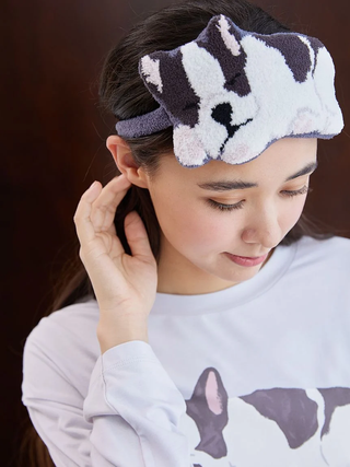 Woman wearing a plush Sleeping Dog eye mask with playful motif designed for comfort and whimsy.