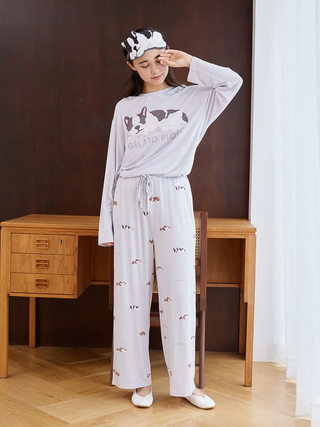 Woman wearing Gelato Pique pajamas and Sleeping Dog eye mask in a stylish bedroom setting.