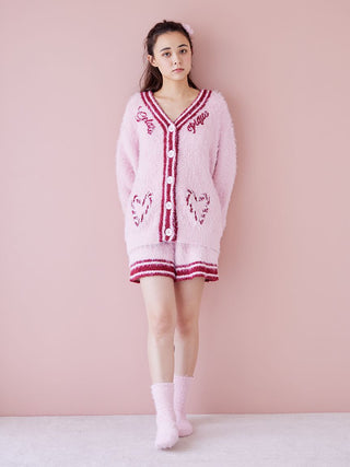 Model wearing pink Gelato Pique cardigan and shorts set, paired with matching socks and fur hairpin, standing against a pink background.