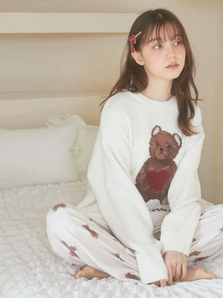 Model wearing Gelato Pique sweater and heart hairpin set, sitting on a bed in cozy pajamas.