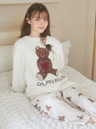 Woman in Gelato Pique teddy bear pajamas and heart hairpin sitting on a white bed, smiling.