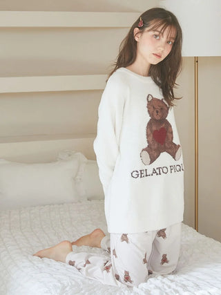 Woman wearing Gelato Pique sweater with heart hairpin, posing on bed with bear print pajamas.