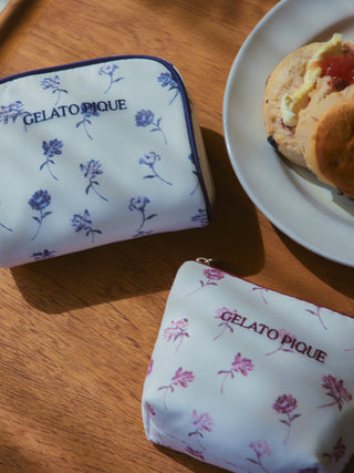 Rose patterned square pouch by Gelato Pique with vintage floral design on wood table next to scone, embodies elegance and functionality.