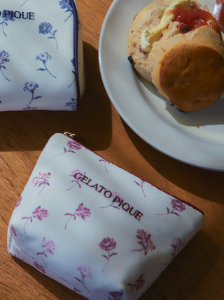 Gelato Pique rose-patterned tissue pouches on a wooden table beside a plate with a scone.