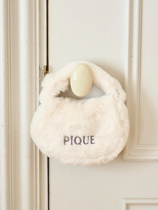 White faux fur mini handbag with "PIQUE" logo, soft and fluffy texture, hanging on a white door, ideal for winter fashion.