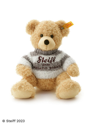Steiff plush teddy bear wearing a cozy sweater with logo tag, showcasing timeless quality and craftsmanship.