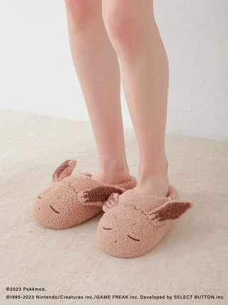 Person wearing Pokémon Sleep Baby Moco Eevee room shoes, cozy slipper design featuring Eevee's face and ears, on a soft beige carpet.
