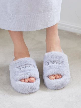 Person wearing Gelato Pique Eco Fur Fuzzy Slippers in grey, showcasing their ultra-soft faux fur and open-toe design on a carpeted floor.
