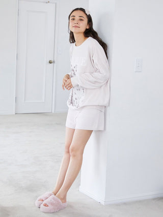 Person lounging in cozy homewear with pink Eco Fur Fuzzy Slippers, showcasing a relaxed and comfortable look in a bright, minimalist room.