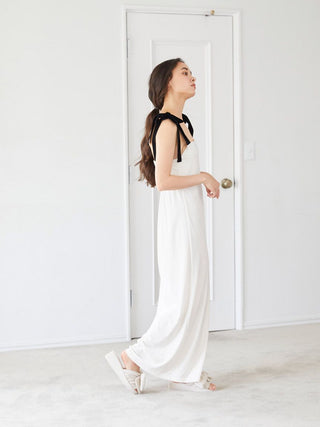 Woman in a white dress standing in a bright room, showcasing minimalist style and elegance.