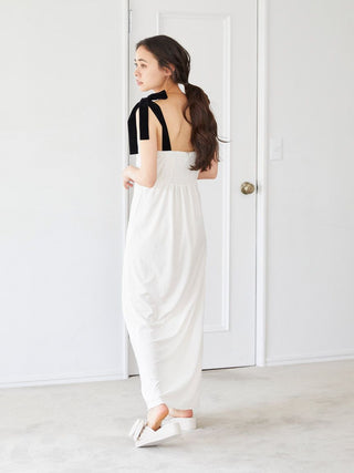 Woman in a white dress wearing luxury velvet bow slip-on shoes, standing indoors against a white door.