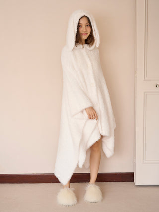 Person wearing white faux fur hooded robe and fluffy slippers, standing indoors.