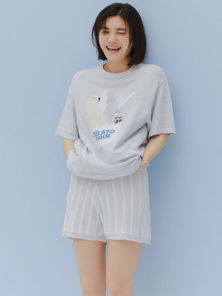 Woman wearing COOL Striped Lounge Shorts with light blue stripes on white, paired with a cozy graphic tee, smiling against a blue background.