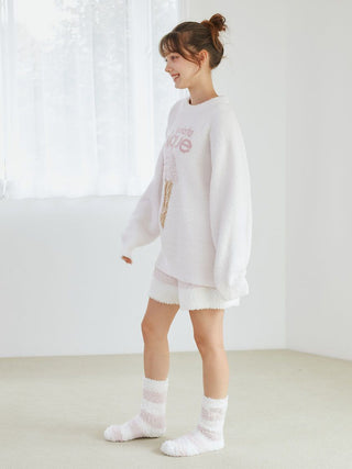 Woman wearing cozy Gelato 2 Border Lounge Shorts and matching top, standing in a bright room with soft natural light.