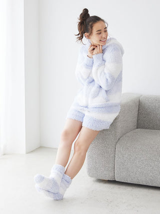 Woman wearing Gelato 3 Border Lounge Shorts in fluffy fabric and pastel colors, sitting on a couch, exuding comfort and style.