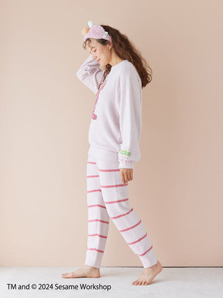 Woman wearing Sesame Street motif jacquard pullover and long pants set in pink and white stripes, made with Baby Moco fabric.