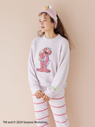 Woman wearing Sesame Street jacquard pullover with Elmo design and striped long pants, made from soft Baby Moco fabric.