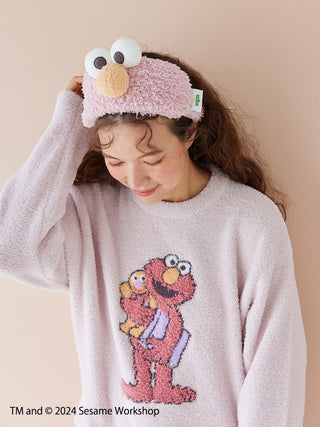 Woman wearing Sesame Street motif jacquard pullover with Elmo design and matching Elmo-themed headband.