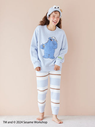 Woman wearing a Sesame Street motif jacquard pullover and long pants set featuring Baby Moco fabric, with a Cookie Monster design.
