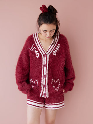 Woman wearing a burgundy feather button-up cardigan with festive ribbed trim, showcasing luxurious warmth and style.