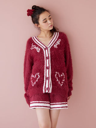 Woman wearing red feather button up cardigan with heart designs and festive trim.