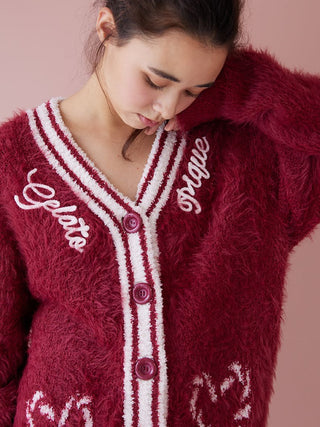Model wearing soft red feather button-up cardigan with festive design and contrasting ribbed trim.