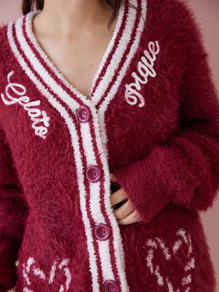 Woman wearing a red feather button up cardigan with ribbed trim and decorative script, offering a cozy and festive winter look.