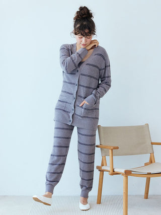 Model wearing Hot Smoothie Border Cardigan with classic striped pattern, standing next to a chair.