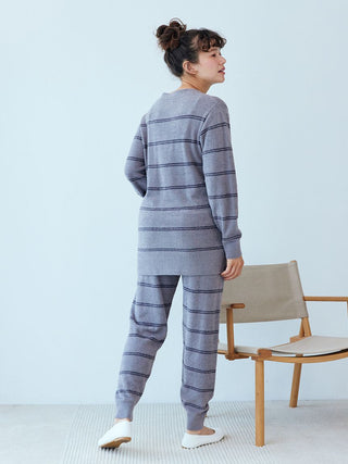 Woman wearing Gelato Pique Hot Smoothie Border Cardigan and pants, showcasing cozy striped outfit in a modern setting.
