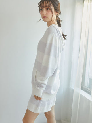 Woman wearing a Smoothie 2-Border Zip-Up Hoodie in a cozy indoor setting, showcasing its soft and stylish design with light 2-border stripes.