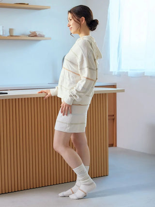 Woman wearing Smoothie Colorful Zip-Up Hoodie in cozy indoor setting, showcasing playful stripes and luxurious comfort from Gelato Pique.