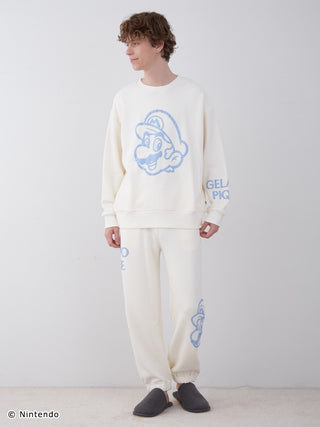 Model wearing Super Mario unisex fleece pullover and long pants set, featuring large Mario print and logos, soft cotton fabric.