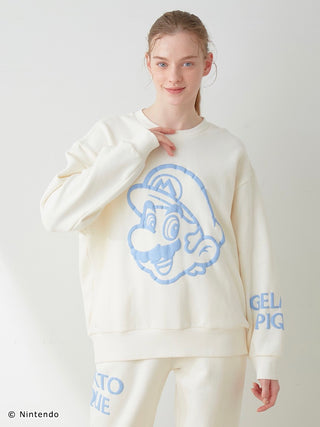Model wearing a SUPER MARIO™️ unisex fleece pullover and pants set with blue Mario print and elasticized hems.