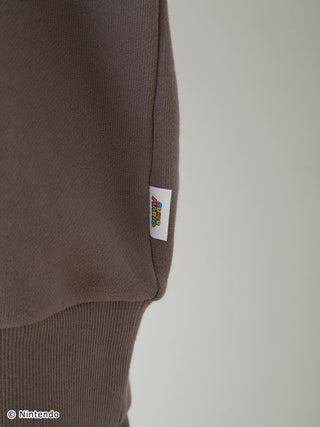 Close-up of Super Mario fleece pullover cuff with logo tag, showcasing soft fabric texture.