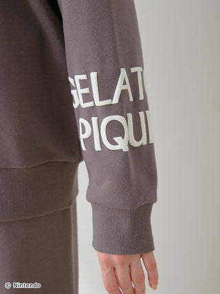 Close-up of sleeve with "Gelato Pique" logo on SUPER MARIO™️ unisex fleece pullover from the sweatshirt and pants set.