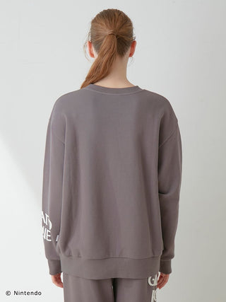 Back view of a person wearing a grey UNISEX Fleece Pullover from the SUPER MARIO™️ set, featuring printed logos on the sleeves.