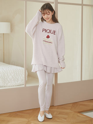 Woman wearing leggings with a chic balloon skirt and cozy sweater, standing in a bright room, showcasing a modern and versatile outfit.