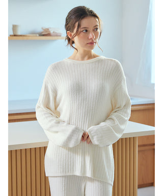 Woman wearing a white Thermal Smoothie Pullover Sweater with ribbed texture, standing in a bright room.