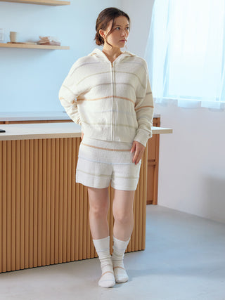 Woman wearing Smoothie Colorful Border Lounge Shorts and matching hoodie by Gelato Pique USA, standing in a cozy room.