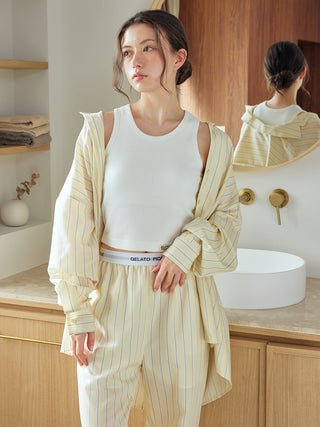 Woman wearing Gelato Pique USA striped long sleeve pajama shirt with elegant, relaxed design, standing in a modern bathroom.